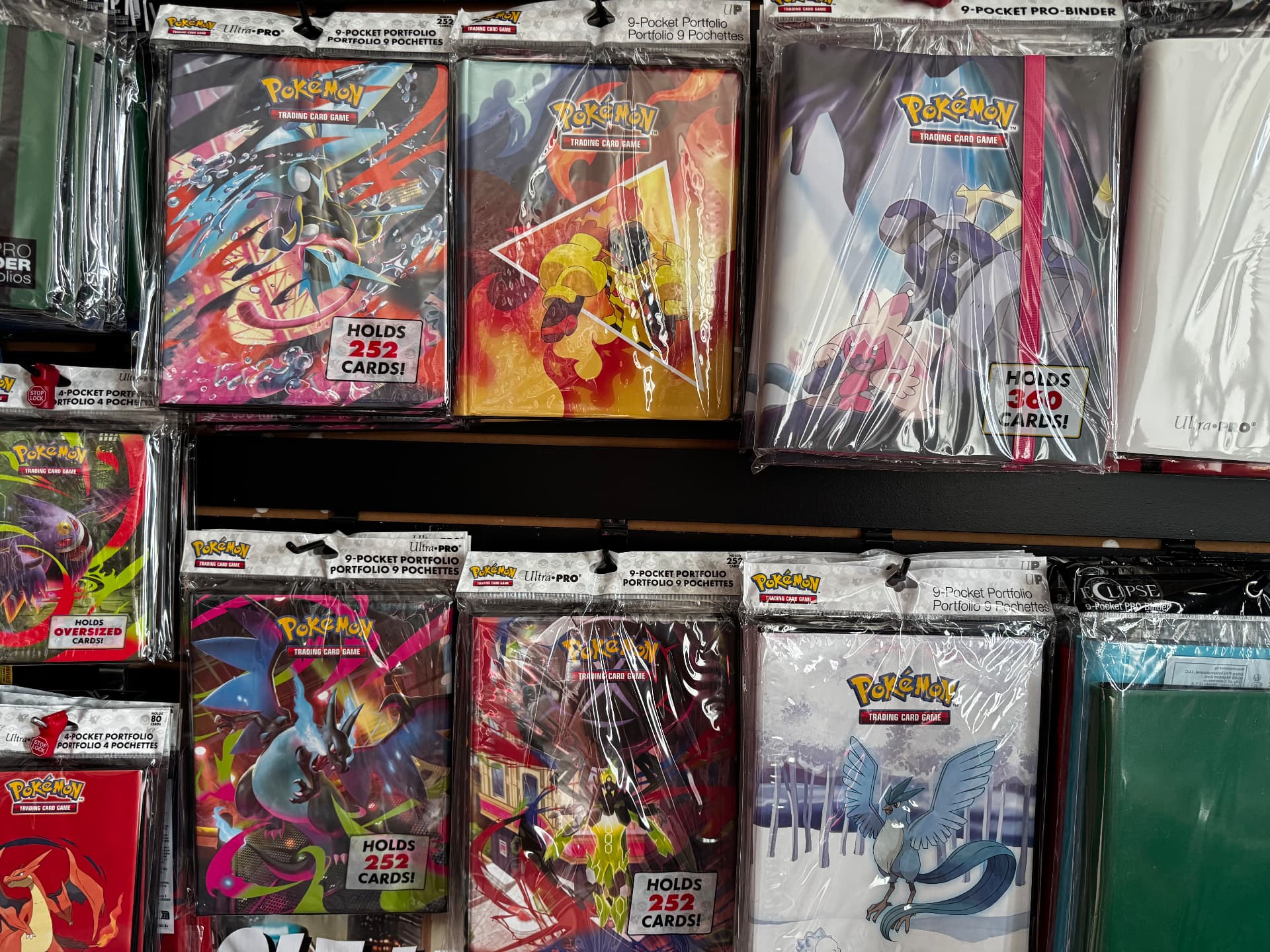 Pokemon card binders and portfolios on the wall at CGX